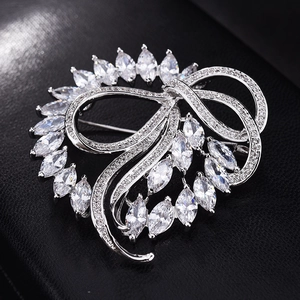 Détail macro d'une broche nœud en argent avec zircons marquise sur texture cuir noir