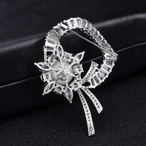 Détail macro d'une broche perle avec incrustation de zircon et élégants pompons argentés