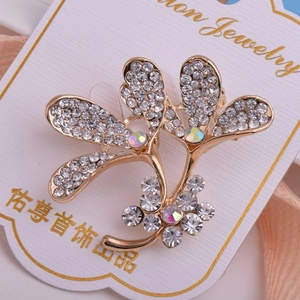 Détail macro d'une broche dorée en forme de feuille avec strass brillants et cristaux AB