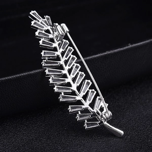 Silver leaf brooch with baguette-cut zircons on a black textured background
