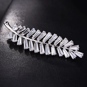 Macro shot of silver leaf brooch with micro-paved cubic zirconia crystals on black leather