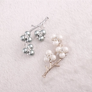 Elegant floral branch brooches with faux pearls and crystals on soft white fur background