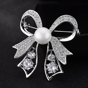 Elegant silver bow brooch with a large pearl center and sparkling cubic zirconia stones