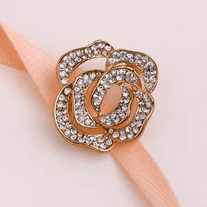 Détail macro d'une broche rose dorée avec strass en cristal étincelants sur carte