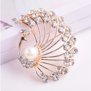 Detailed close-up of a golden peacock brooch with sparkling zircons and white pearl