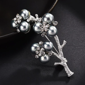 Macro detail of branch-shaped silver brooch with gray pearls and sparkling rhinestones
