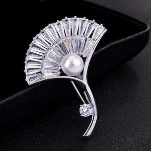 Macro shot of silver fan brooch with baguette-cut zircons and a white pearl accent