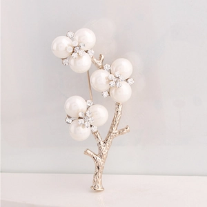Detail of floral branch brooch featuring faux pearls and crystal encrusted flower centers