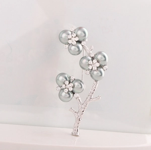 Macro detail of plum blossom brooch with grey faux pearls and sparkling rhinestones