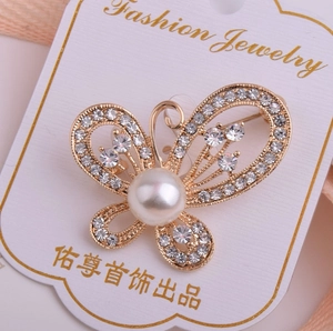 Vue détaillée de la broche papillon avec strass étincelants et perle blanche centrale