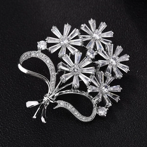 Macro view of bouquet brooch with cubic zirconia flowers and a ribbon bow on black leather