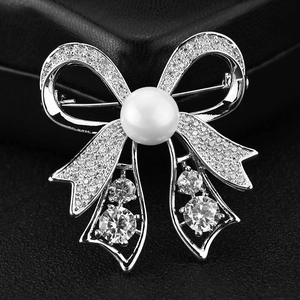 Sparkling silver bow brooch with pavé zircon stones and a large center pearl on black leather