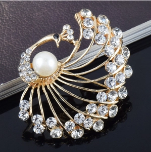 Elegant vintage peacock brooch with white rhinestones and a central faux pearl inlay