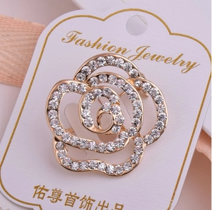 Gros plan d'une broche rose dorée évidée avec strass étincelants sur carte de bijoux