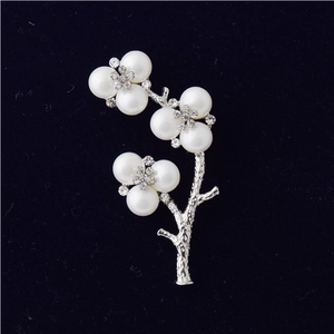 Macro detail of silver floral brooch with white pearls and sparkling rhinestones