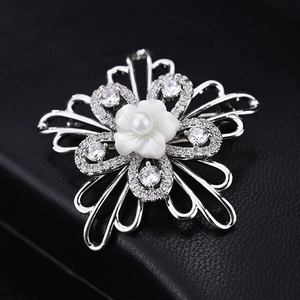 Macro shot of silver flower brooch with shell petals, AAA zircon, and white pearl