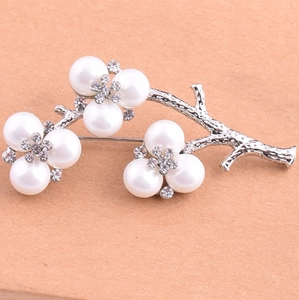 Detailed view of elegant silver floral brooch with white pearls and sparkling rhinestones