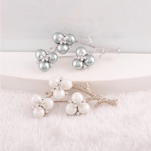 Macro view of silver and gold branch brooches with faux pearls and sparkling rhinestones