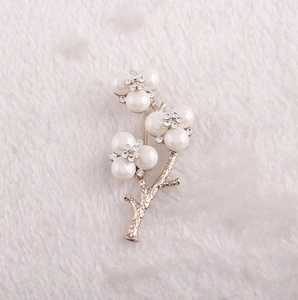 Detailed view of the gold flower branch brooch with pearl petals and rhinestone accents