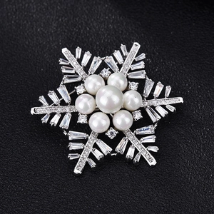 Detail view of snowflake brooch with pearls and zircon on black leather texture