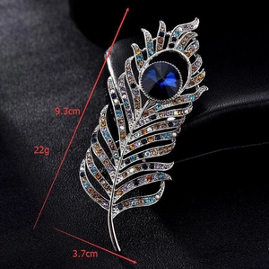 Macro shot of colorful rhinestones on a peacock feather brooch with a large blue center gem