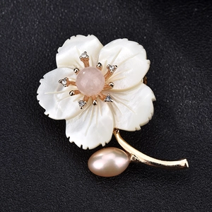 Détail macro de broche fleur en nacre avec perle rose et accents de strass brillants