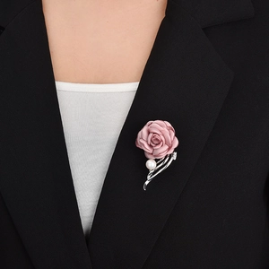Detail of a dusty rose fabric flower brooch with pearls and silver tassels on black suit
