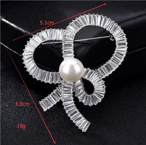 Detailed view of silver bow brooch with zircon inlay and pearl, sized 5.5cm by 5.1cm