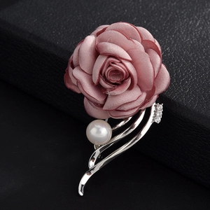 Macro shot of elegant fabric camellia flower brooch with pearl and silver branch detail