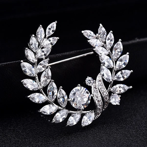 Elegant silver laurel leaf brooch with sparkling zircons on dark velvet background