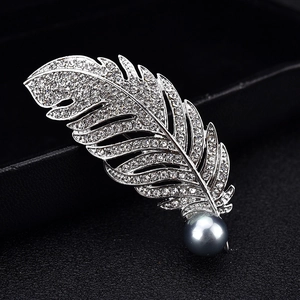 Elegante silberne Federbrosche mit funkelnden Kristallen und einer grauen Perle