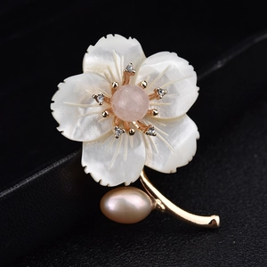 Détail de la broche fleur en nacre avec pierre rose et perle sur cuir noir