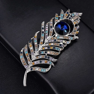 Macro detail of elegant peacock feather brooch with blue crystal and colorful rhinestones