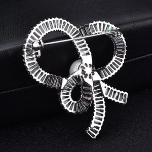 Elegant silver bow brooch with micro-pave zircons and white pearl on dark leather