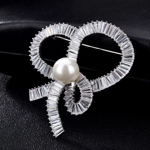Macro shot of silver bow brooch with pavé cubic zirconia and a round white pearl