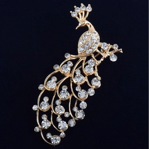 Elegant gold peacock brooch featuring intricate crystal rhinestones on a black background