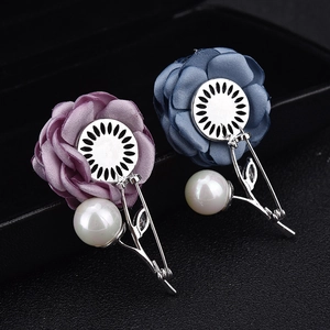 Detail of fabric rose brooches with crystal leaves and large white pearl pendants
