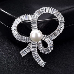 Macro detail of luxury bow brooch with micro-pave zircons and central white pearl