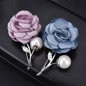 Close-up of fabric rose brooches with white pearls and marquise zircons on black leather