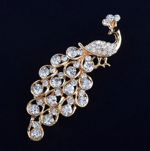 Elegant gold peacock brooch with sparkling white crystals on a premium black velvet background