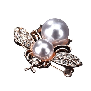 Élégante broche abeille dorée avec cristaux étincelants et perles nacrées sur fond blanc