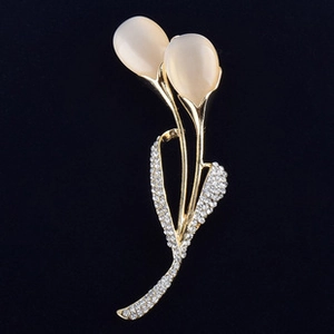 Detail view of a gold tulip brooch featuring cat eye stones and sparkling rhinestones
