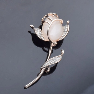 Detailed macro of a rose flower brooch featuring rose gold finish and opal-like gemstone