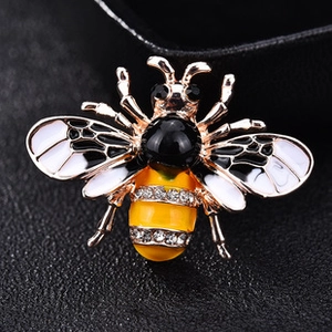 Macro shot of rose gold bee brooch featuring black enamel wings and white crystal detailing
