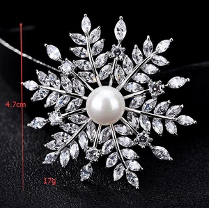 Vue détaillée d'une broche flocon de luxe avec perle, zircons et diamètre de 4.7cm environ