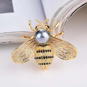 Makroaufnahme der goldenen Bienenbrosche mit grauer Perle und funkelnden Zirkonia-Flügeln