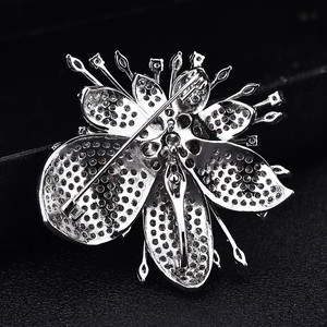 Back view of silver leaf brooch with zirconia stones and pin fastening on black background