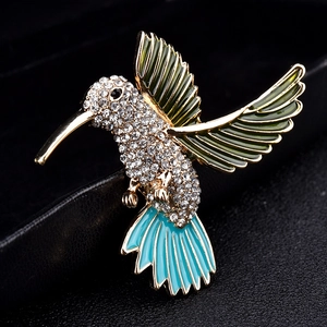 Elegant hummingbird brooch with green enamel wings and sparkling crystals on gold alloy