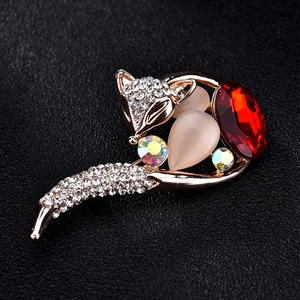 Golden fox brooch with red gemstone and opal cat eye stones on a black leather background