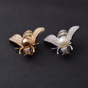 Detail von Bienen-Broschen mit Zirkonia-Flügeln und Perlen auf schwarzem Grund